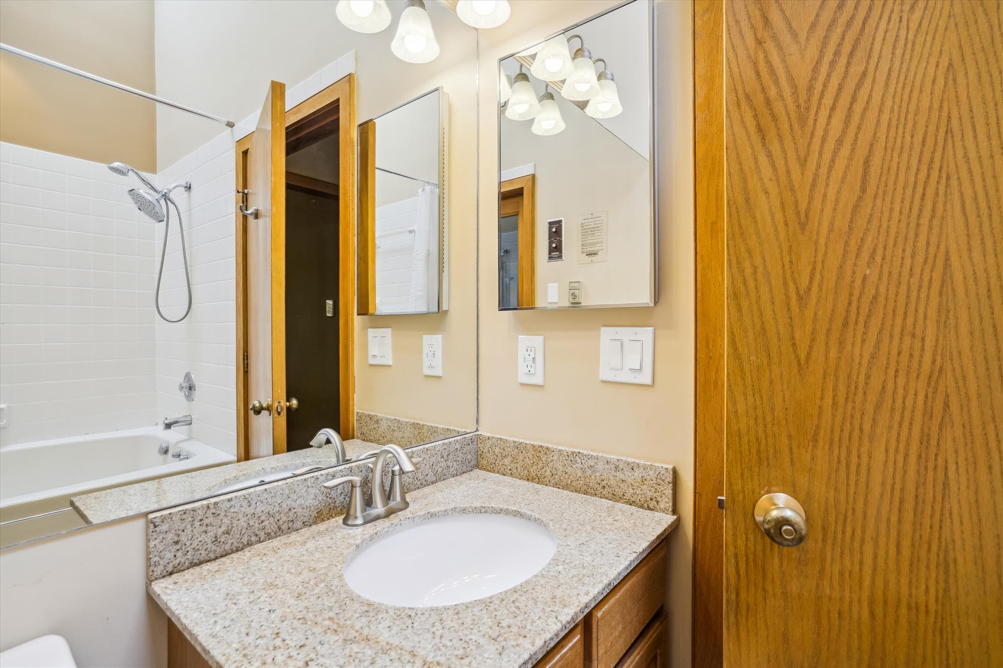 Full bathroom with granite vanity, mirror, and bright lighting.