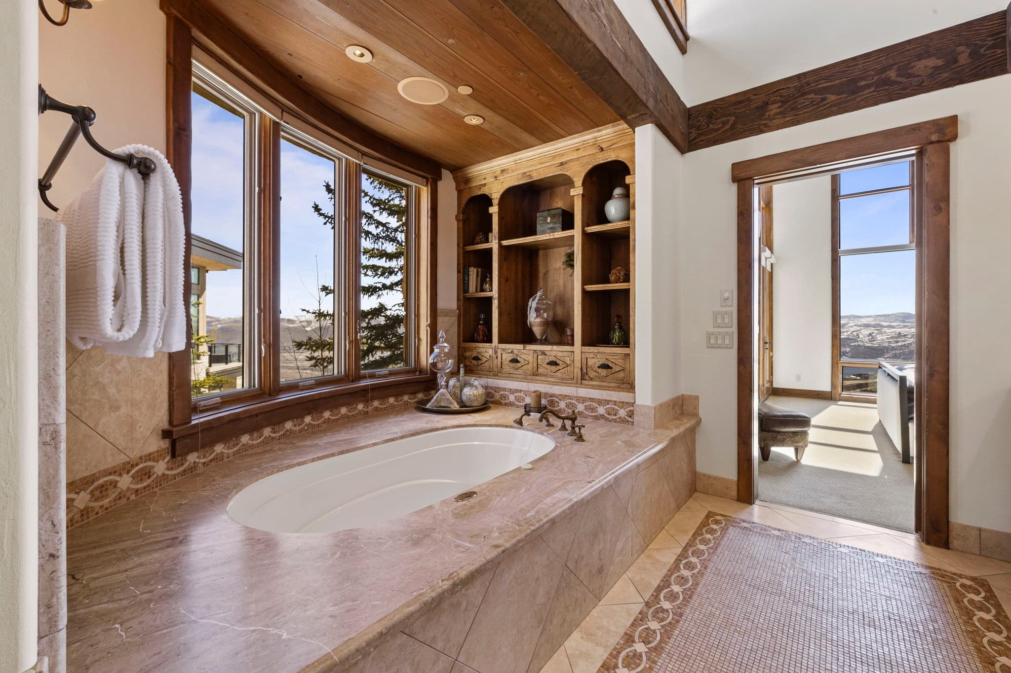 Spa-style bathroom with soaking tub, large windows, and mountain views.