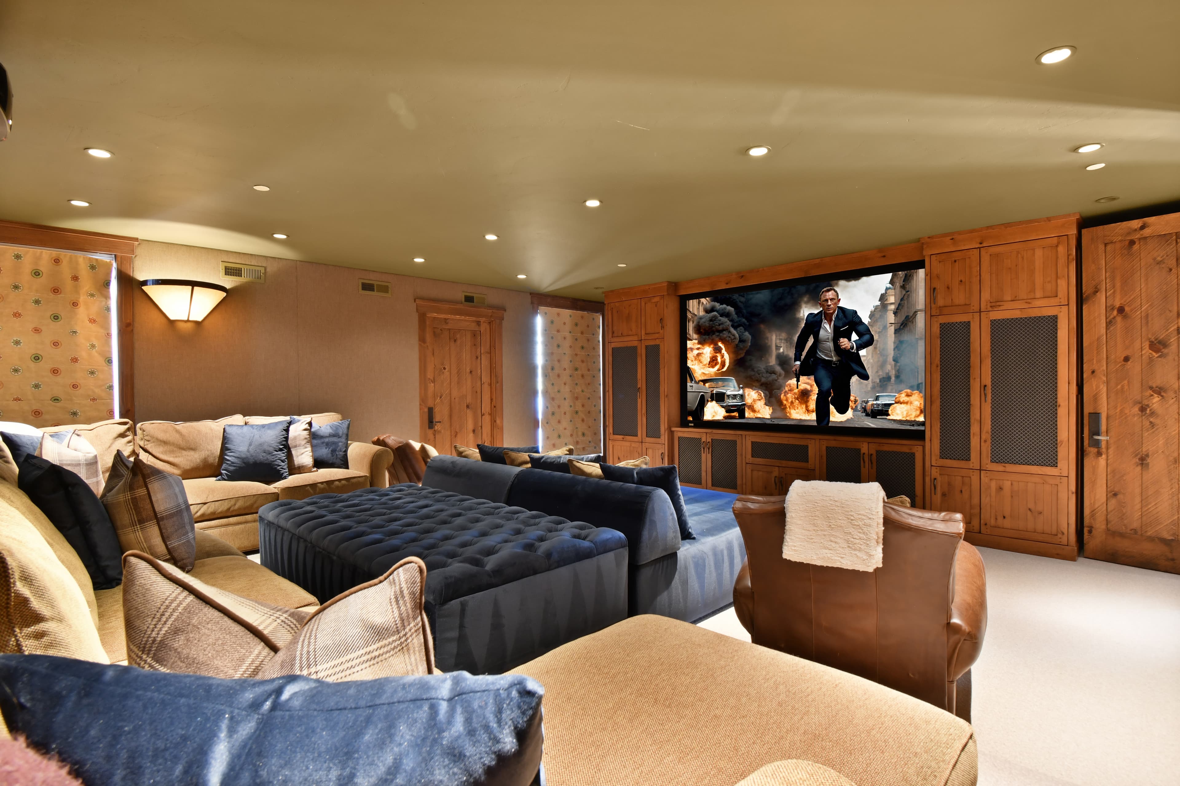 Multiple luxury couches and armchairs sit facing a large TV in the media room.