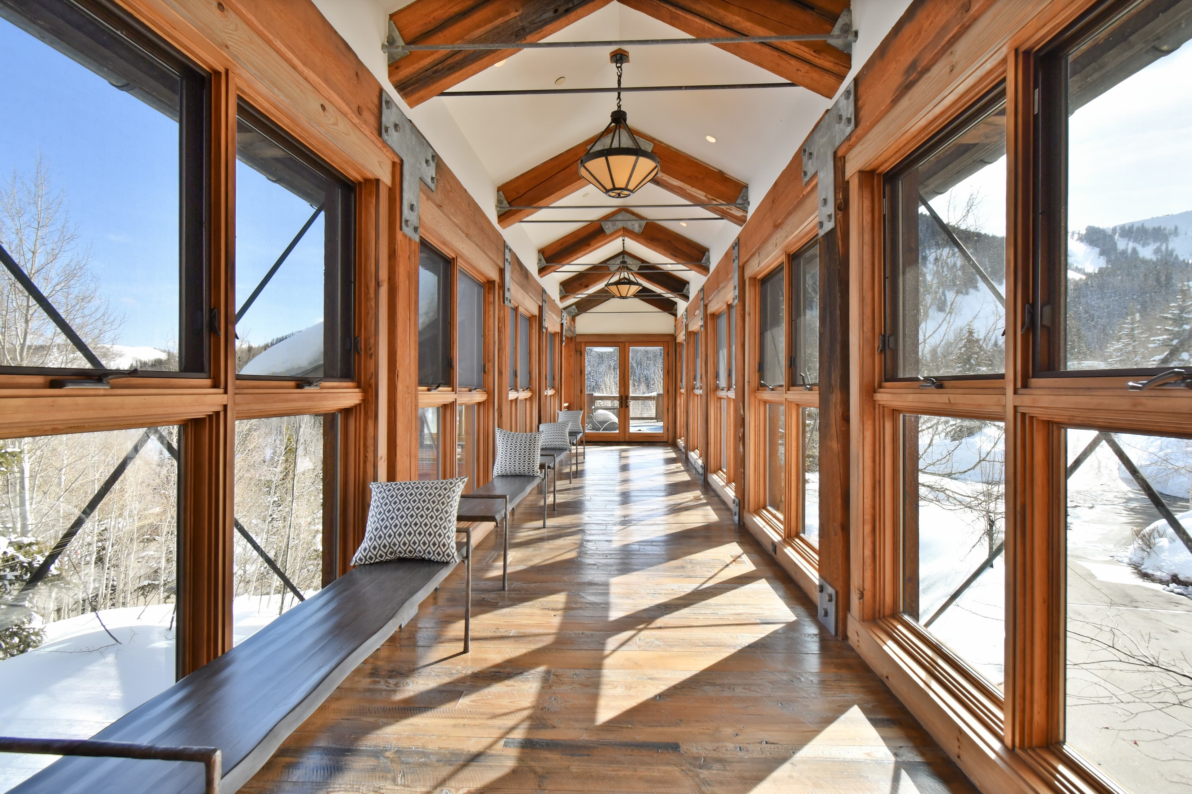 The elevated hallway between two wings of the home, with windowed walls on either side.