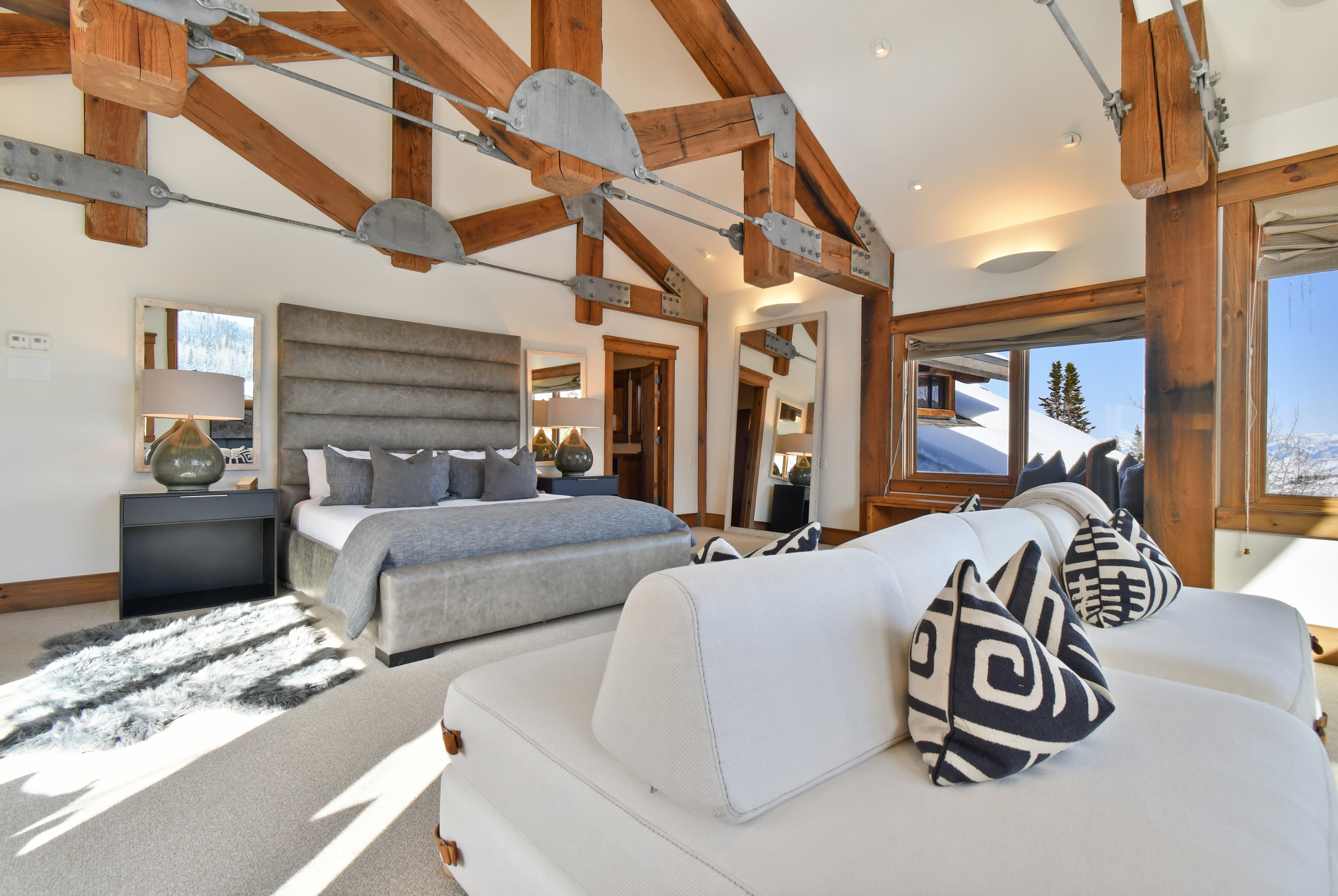 The primary bedroom of Talus Ridge, with a large bed and a personal couch in front of it.