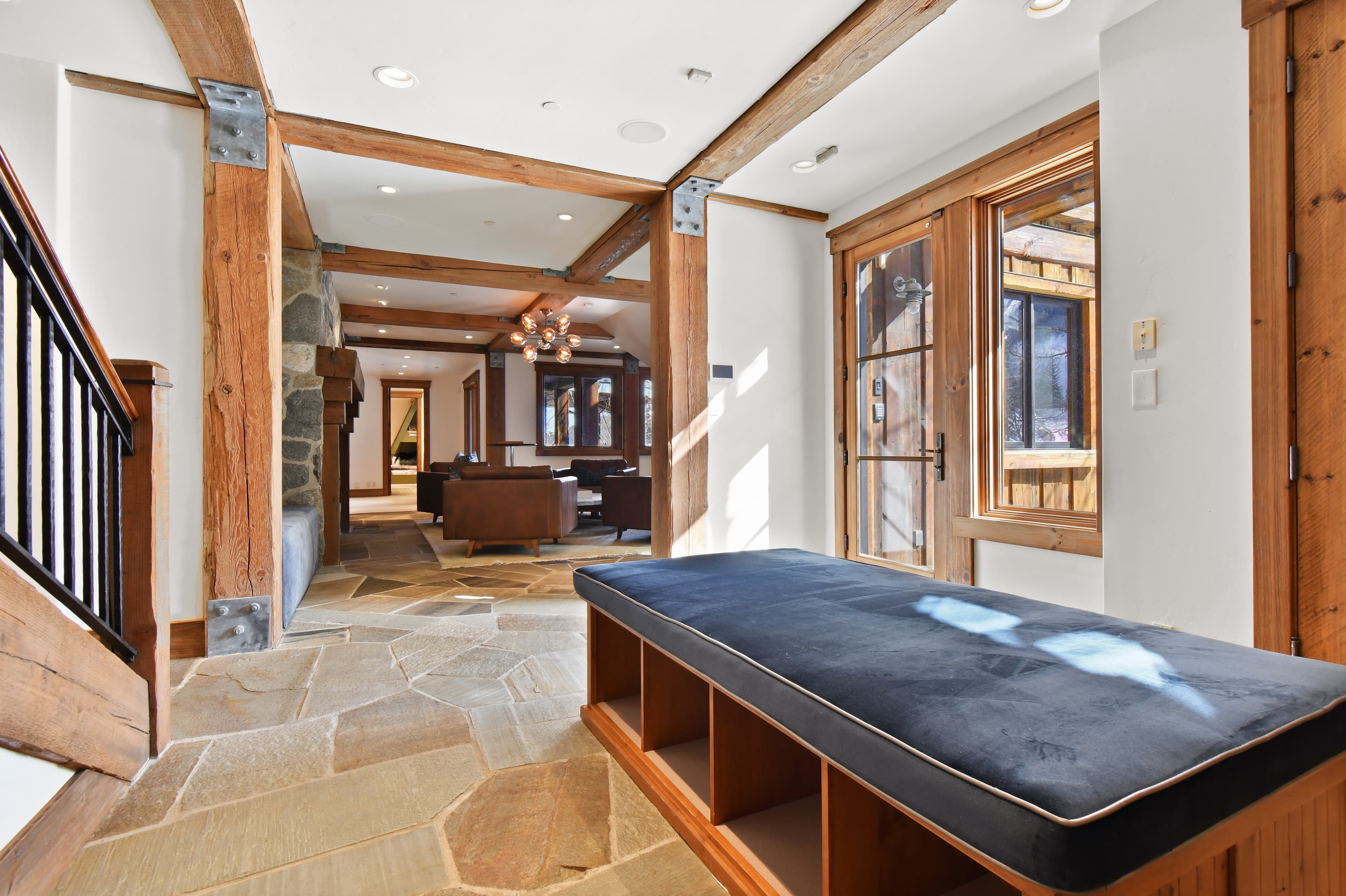A cushioned blue bench sits by the stairs in the entryway of the home.