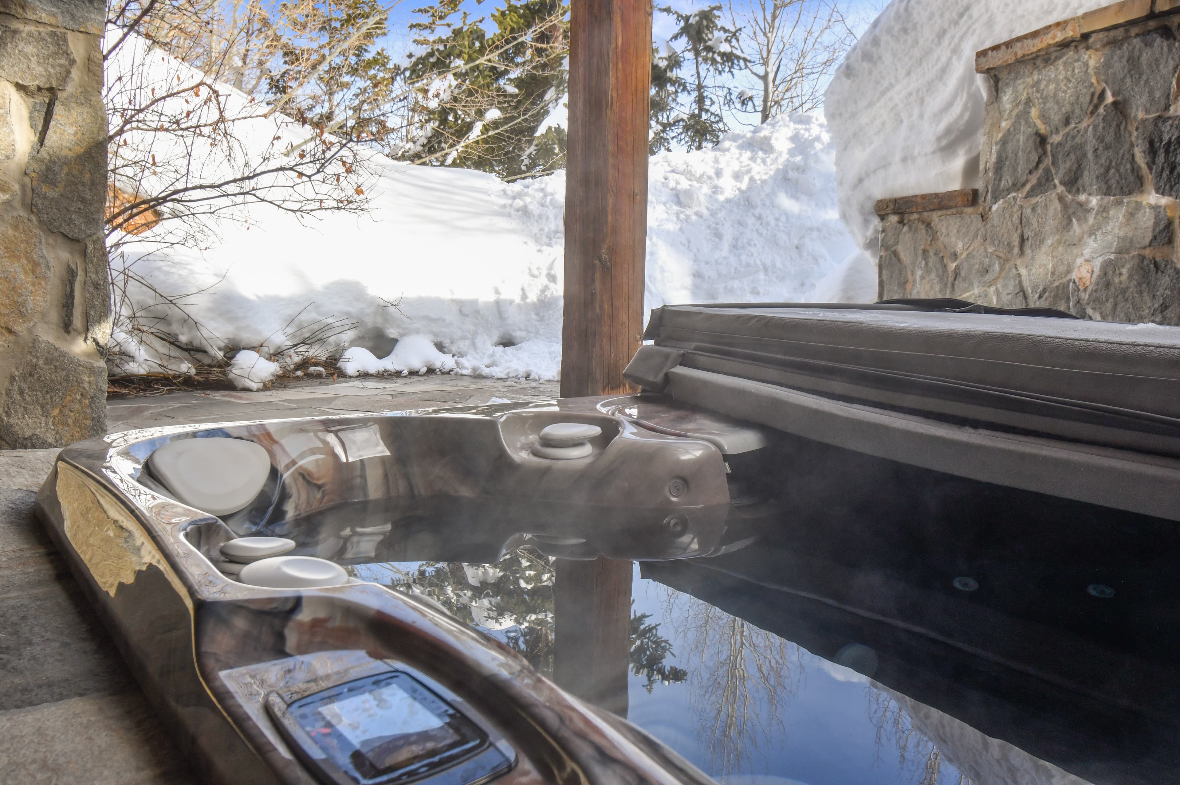 The hot tub of this luxury Park City vacation rental, steaming in the winter weather, surrounded by snow.