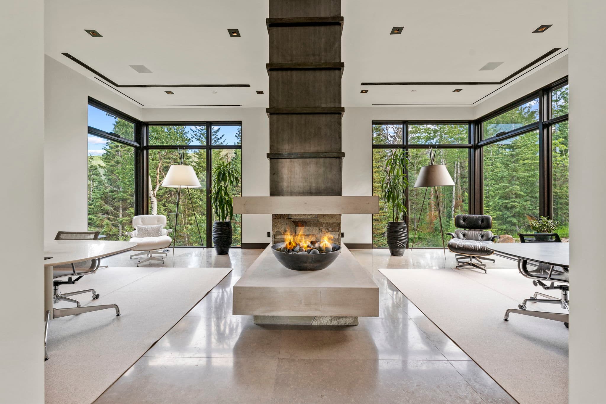 A bright living space with a sleek fireplace and forest views.