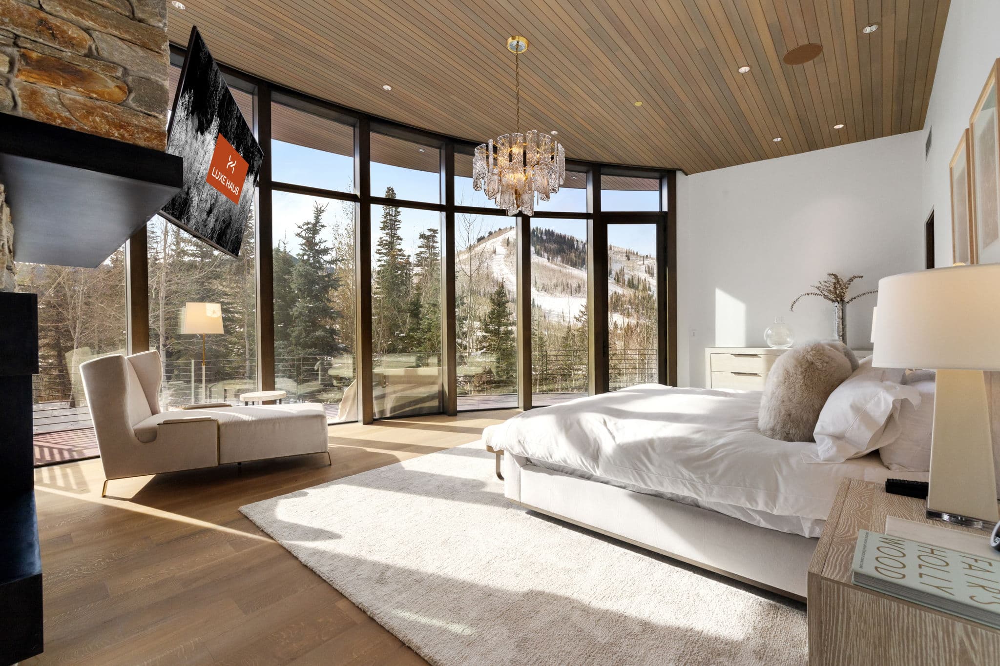 A bedroom with floor-to-ceiling windows and a flatscreen tv.