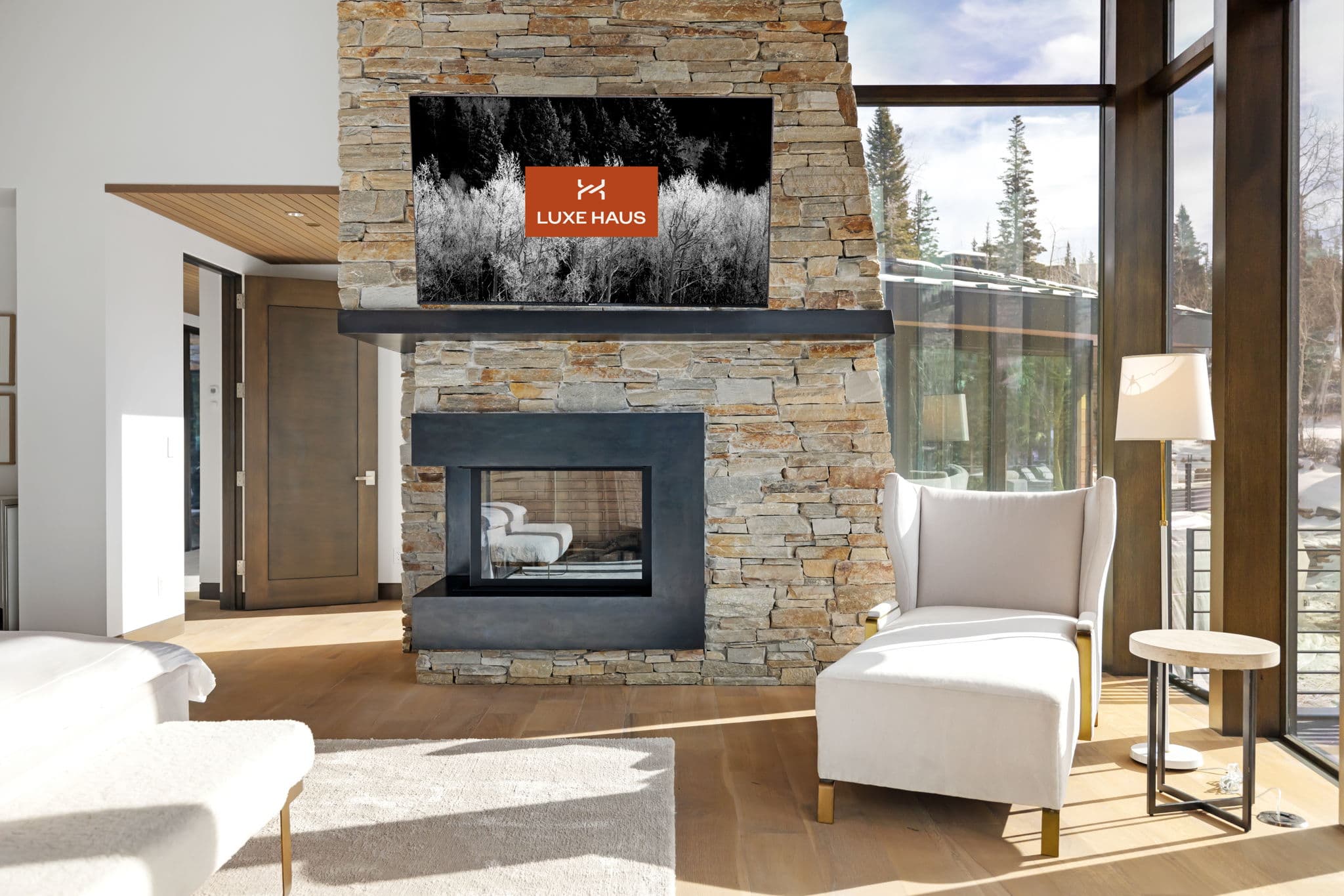 A large bedroom with a fireplace, a flatscreen tv, and a chair.