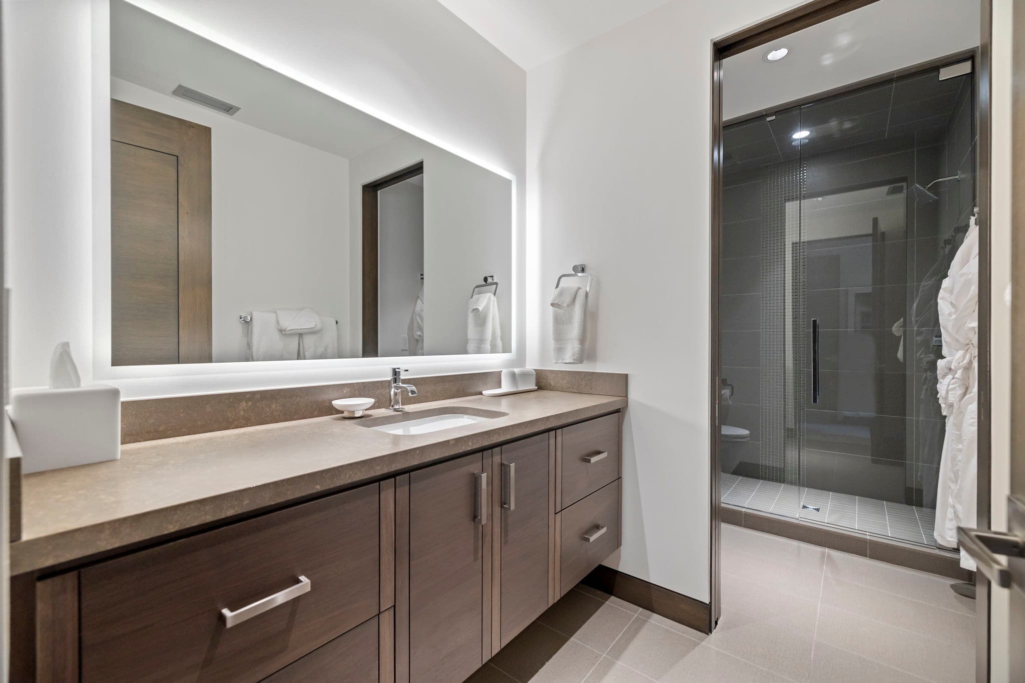 A bathroom with a single sink, a mirror, and a shower.