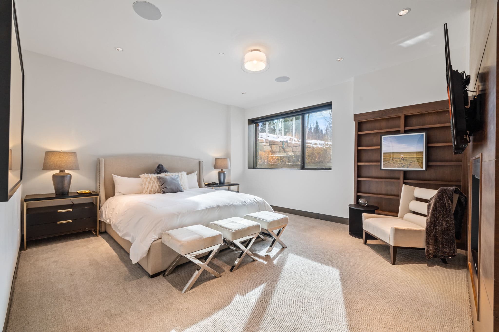 A bedroom with a bed, a side table, and book case.