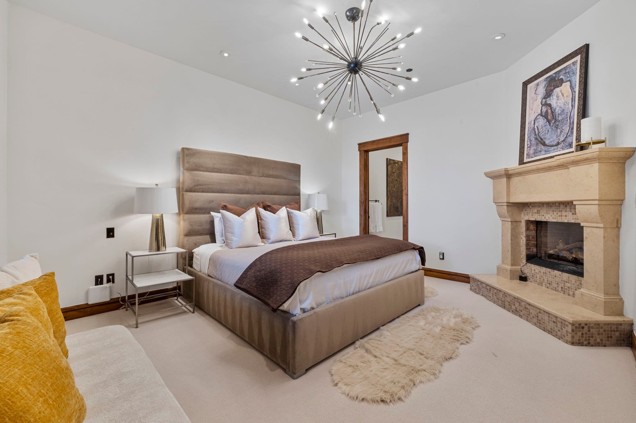 guest suite with queen sized bed, a chandelier and a large stone fireplace