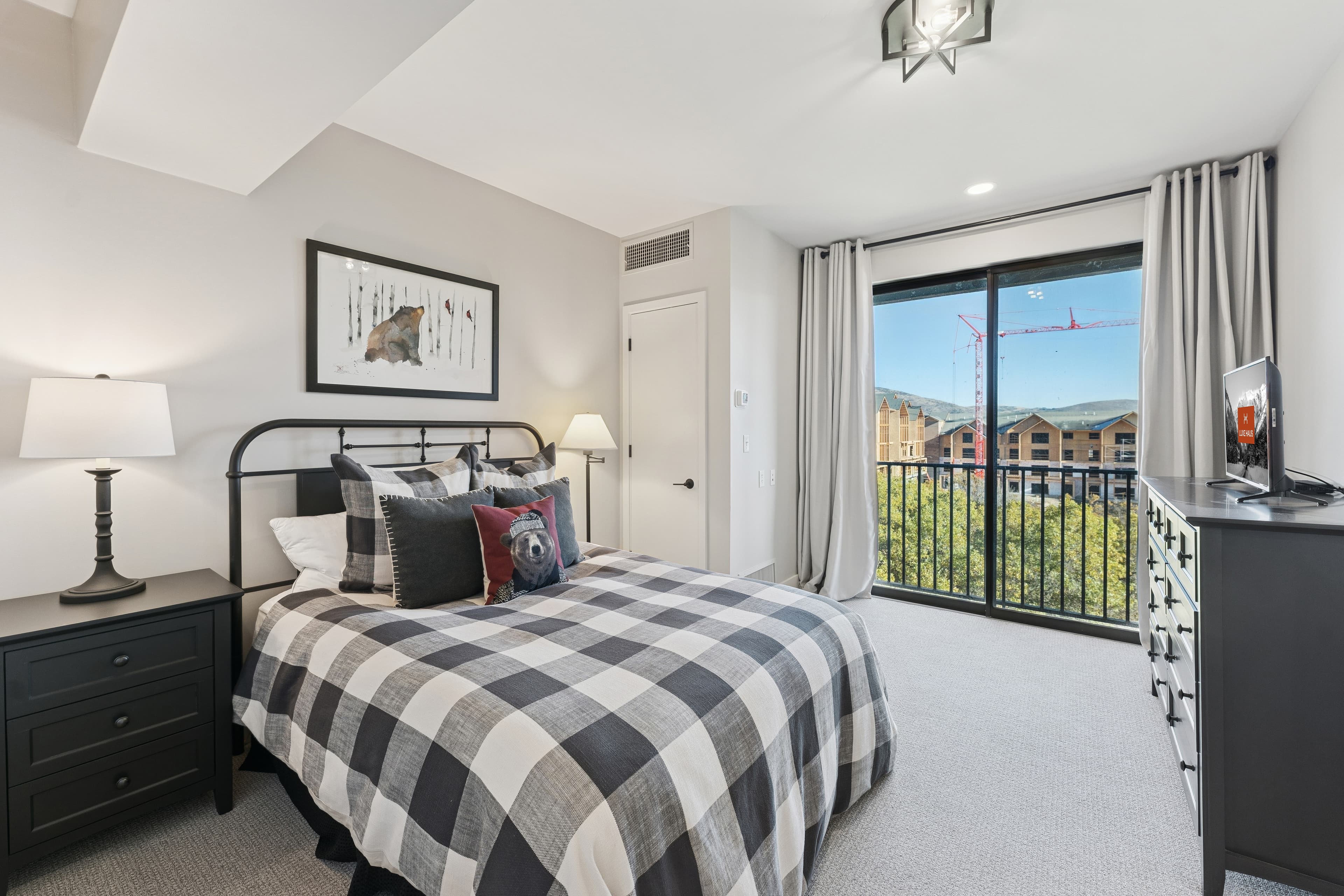 Bright and inviting bedroom with mountain views, a checkered bedspread, and access to a private balcony.