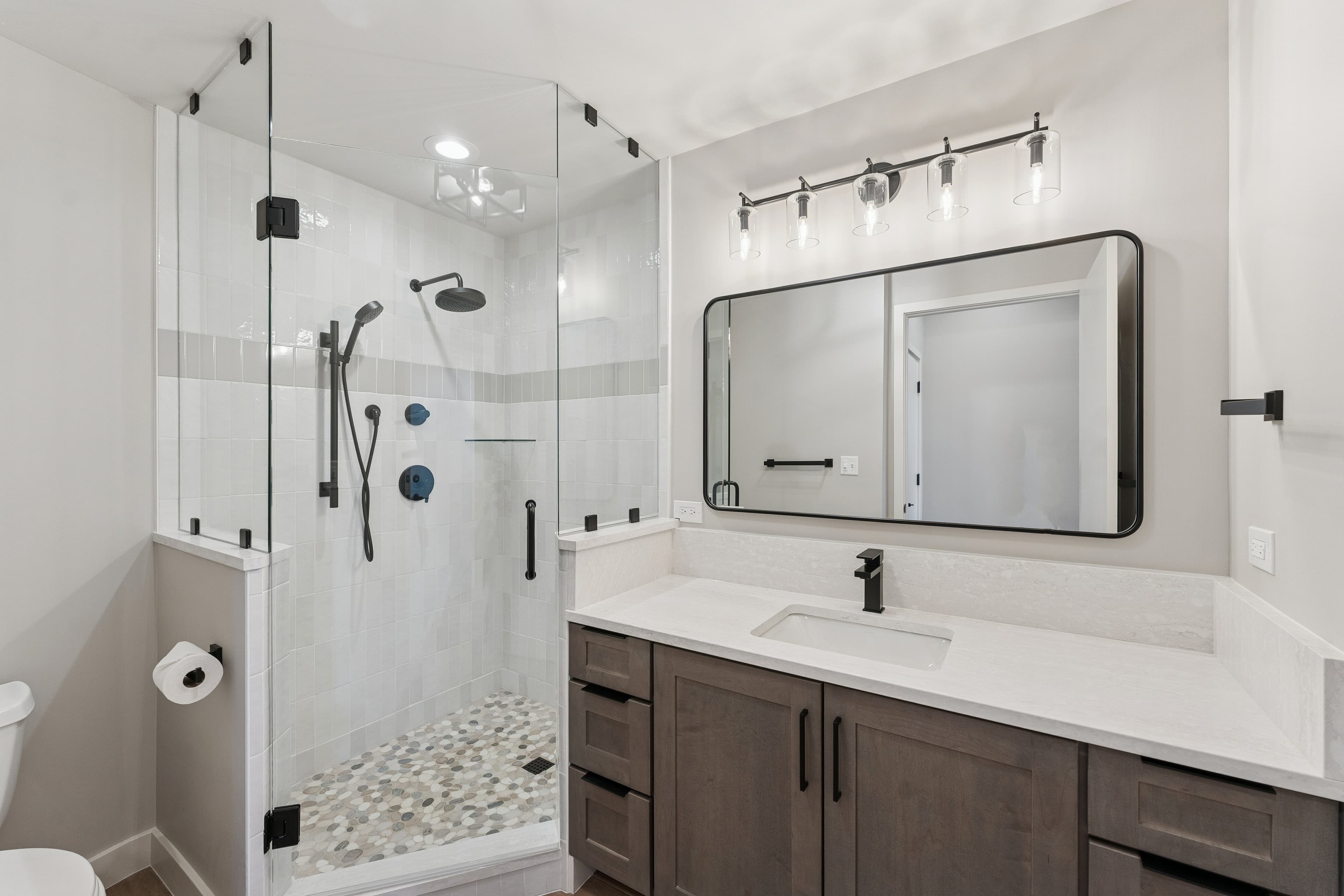 Sleek bathroom with glass-enclosed shower, large vanity, and contemporary lighting.